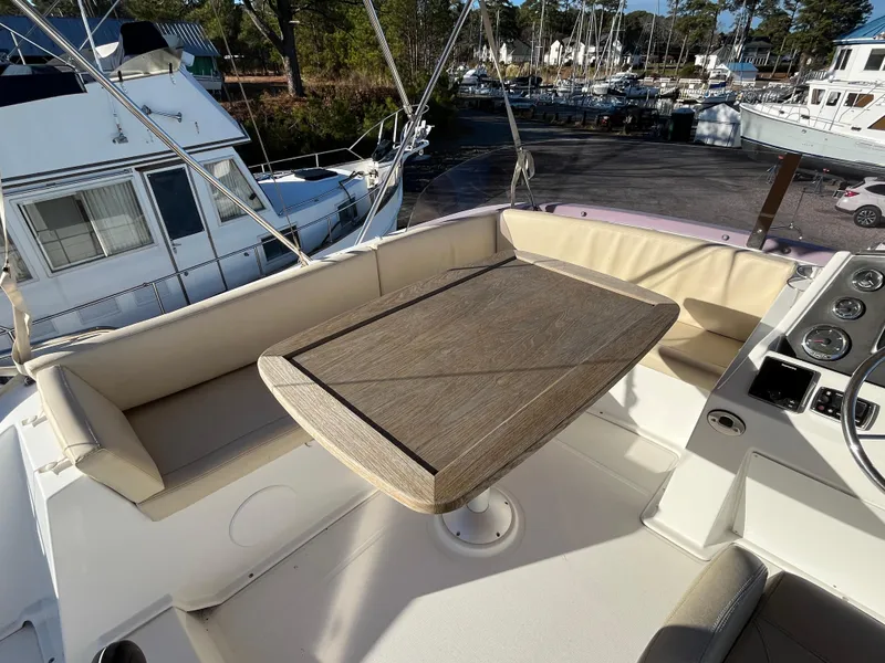 Slide: The Image of Flybridge seating area on 2013 Beneteau Swift Trawler 34 with wooden table and beige cushions. - 36