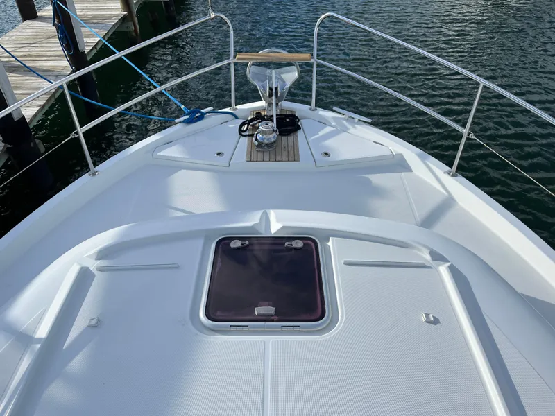 Slide: The Image of 2013 Beneteau Swift Trawler 34 bow view at dock, featuring deck hatch and railing. - 42