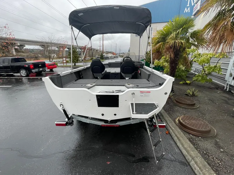Slide: The Image of 2024 Crestliner 1650 Fish Hawk SC boat with canopy, parked outdoors on a rainy day. - 3