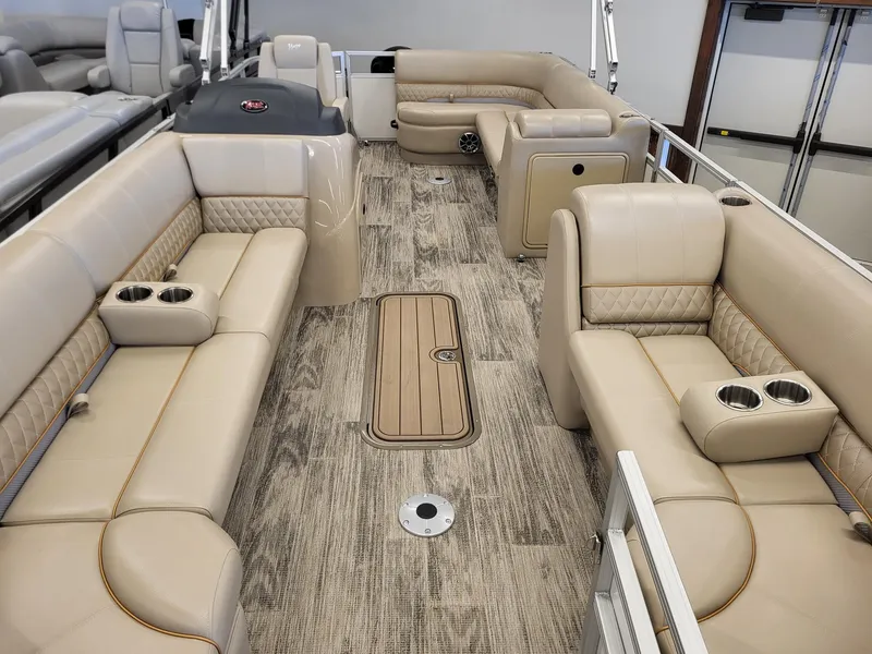 Slide: The Image of 2024 Ranger Reata 223C pontoon boat interior with beige seating and wood-like flooring. - 2