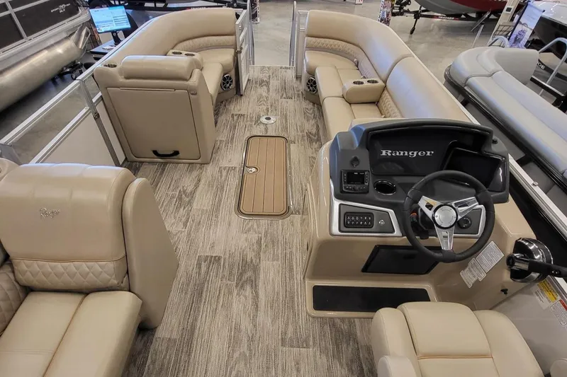 Slide: The Image of 2024 Ranger Reata 223C pontoon boat interior with beige seating and modern dashboard. - 3