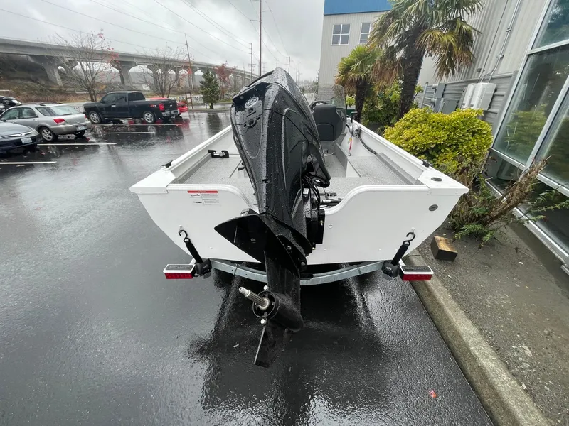 Slide: The Image of 2024 Crestliner 1650 Discovery SC boat with outboard motor in a rainy parking lot. - 3