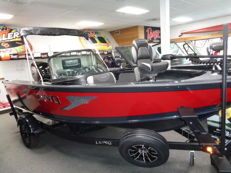 Slide: The Image of 2024 Lund 1775 Crossover XS boat in showroom, red and black design, on trailer. - 1
