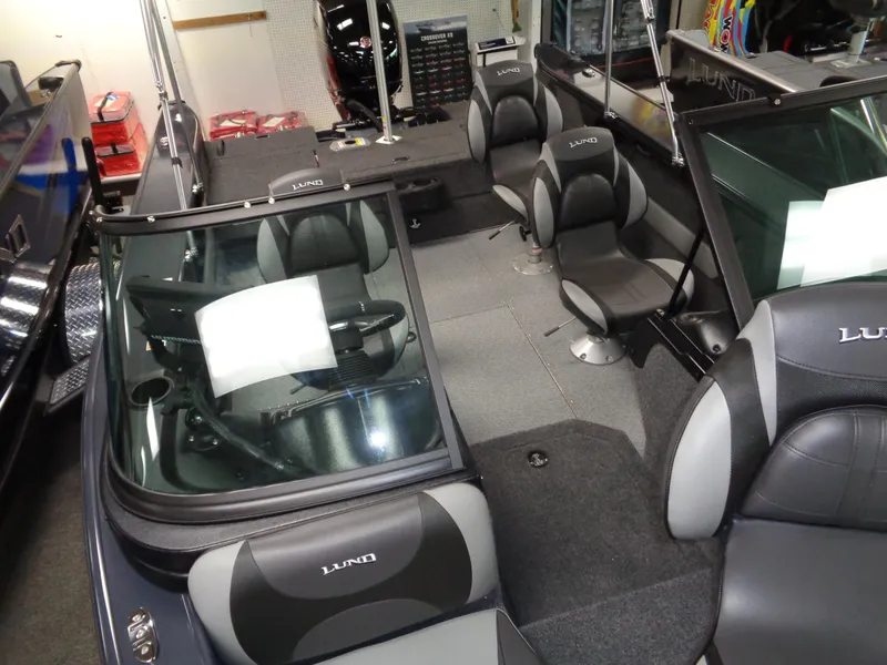 Slide: The Image of 2024 Lund 1775 Crossover XS boat displayed in a showroom with seating and steering console. - 14