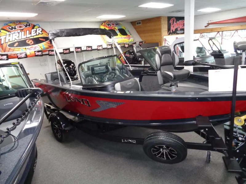 Slide: The Image of 2024 Lund 1775 Crossover XS boat in showroom, red and black exterior. - 2