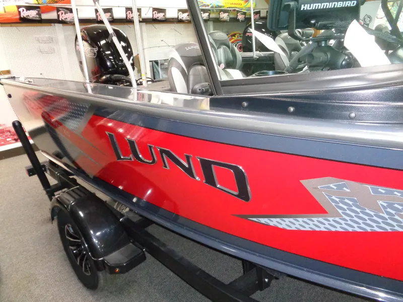 Slide: The Image of 2024 Lund 1775 Crossover XS boat displayed in a showroom with wooden walls. - 3