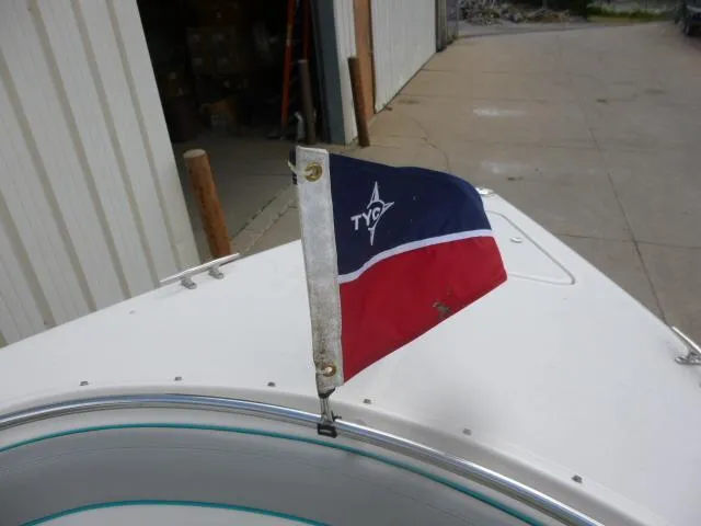 Slide: The Image of Flag on 1992 Tiara Sport 250 boat, docked near a warehouse. - 23