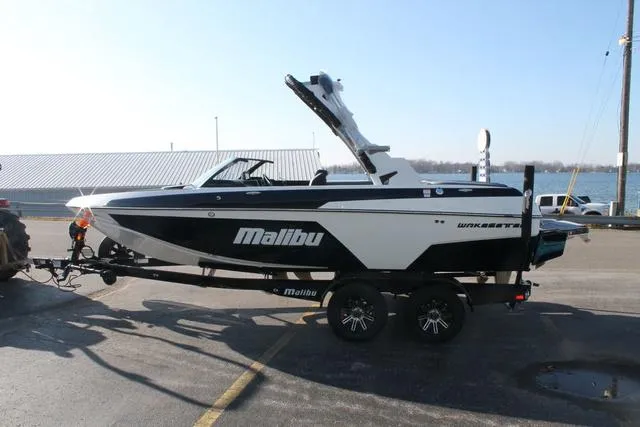 Slide: The Image of 2024 Malibu 20 VTX boat on trailer, parked near waterfront. - 3