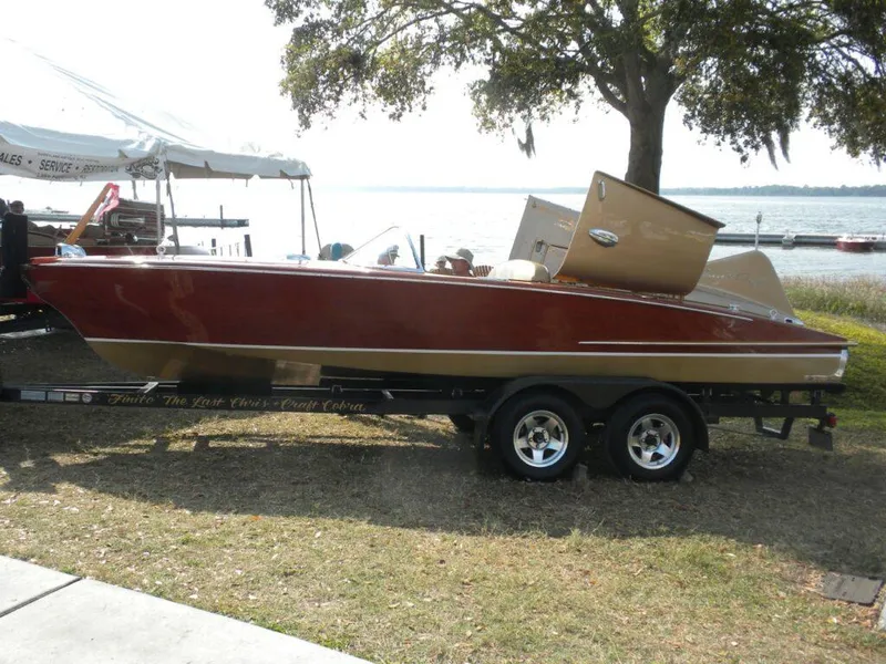 Slide: The Image of 1955 Chris-Craft Cobra 21 boat on trailer by lakeside, under tree shade. - 16