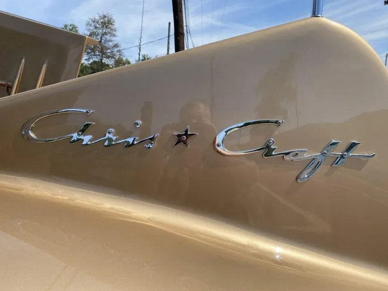 Slide: The Image of 1955 Chris-Craft Cobra 21 boat with chrome logo on a sleek, gold surface. - 17