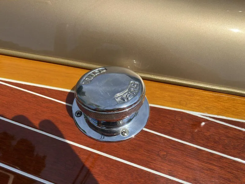 Slide: The Image of 1955 Chris-Craft Cobra 21 fuel cap on polished wooden deck. - 23