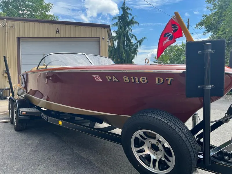 Slide: The Image of 1955 Chris-Craft Cobra 21 boat on trailer, red hull, parked outside a garage. - 3