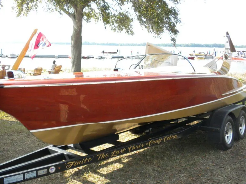 Slide: The Image of 1955 Chris-Craft Cobra 21 boat on trailer, displayed outdoors near a lake. - 30