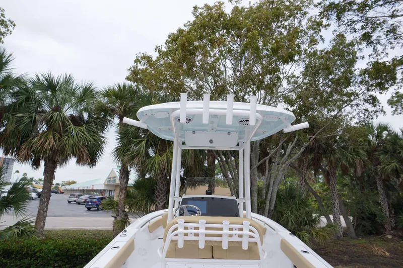 Slide: The Image of 2024 Sportsman 212 Open boat with T-top and rod holders, parked near palm trees. - 25