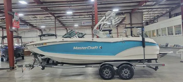 Slide: The Image of 2019 MasterCraft X22 boat in showroom, blue and white design on trailer. - 1