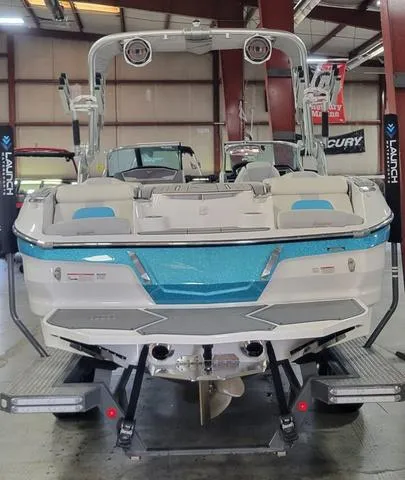 Slide: The Image of 2019 MasterCraft X22 boat in showroom, rear view, blue and white design. - 2