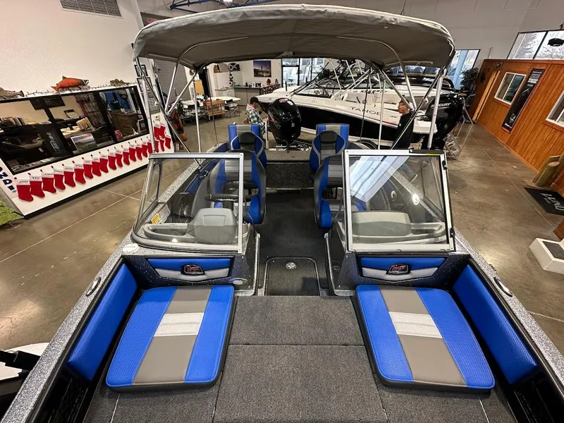 Slide: The Image of 2024 Ranger 1850MS boat interior with blue seating and canopy in showroom. - 14