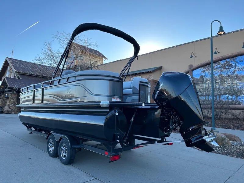 Slide: The Image of 2024 Regency 230 DL3 pontoon boat on trailer, parked outdoors. - 2