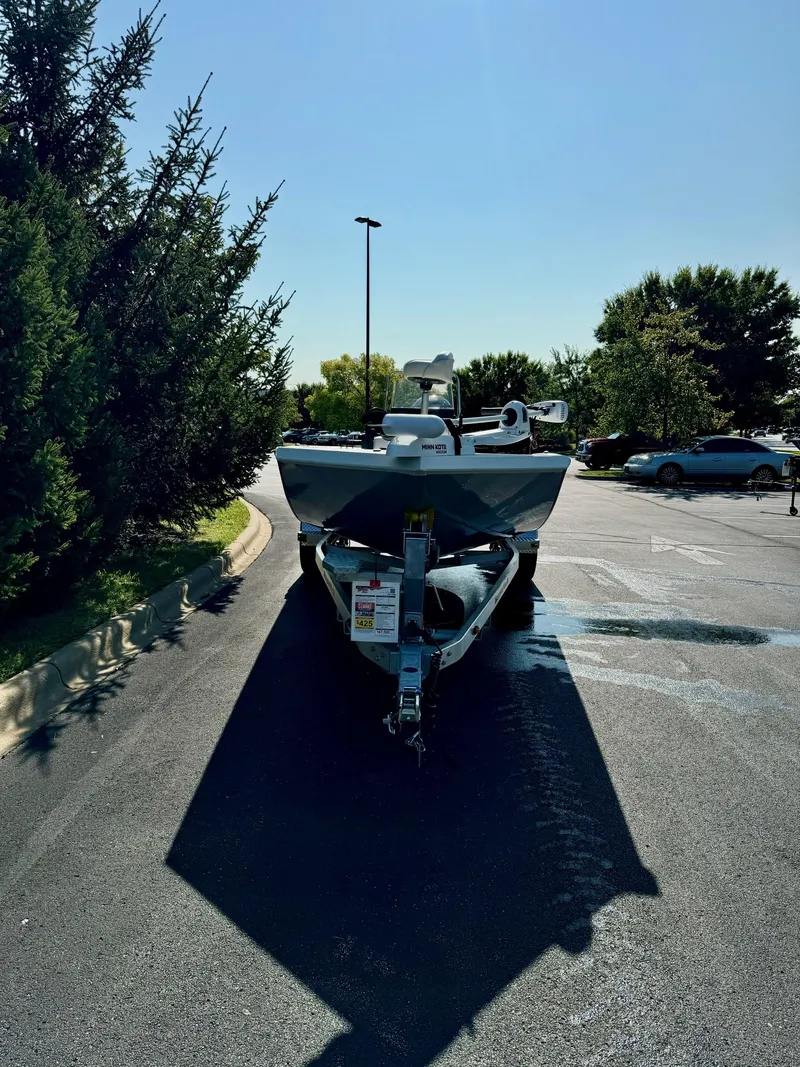 Slide: The Image of 2024 Ranger RB200 boat parked in a sunny lot, surrounded by trees. - 2