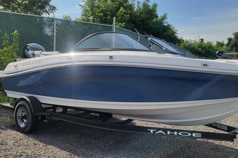 The Image of 2024 Tahoe 200 S boat on trailer, blue and white design, parked outdoors. - 0