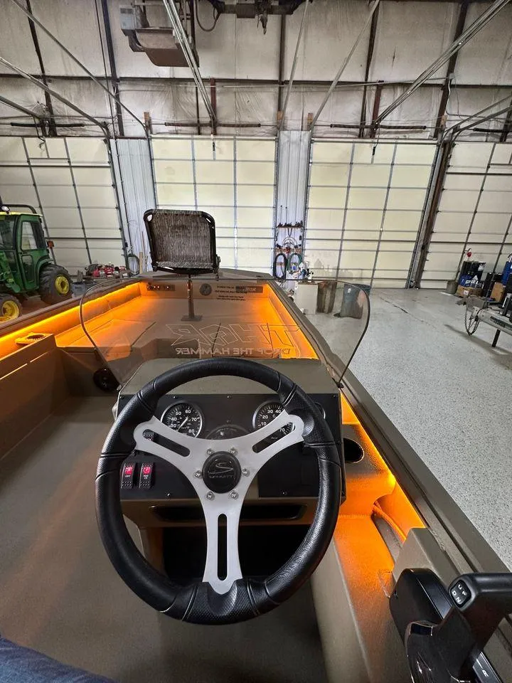 Slide: The Image of 2024 Thor Lake Hammer 1860 SC boat interior with illuminated dashboard in a garage. - 5