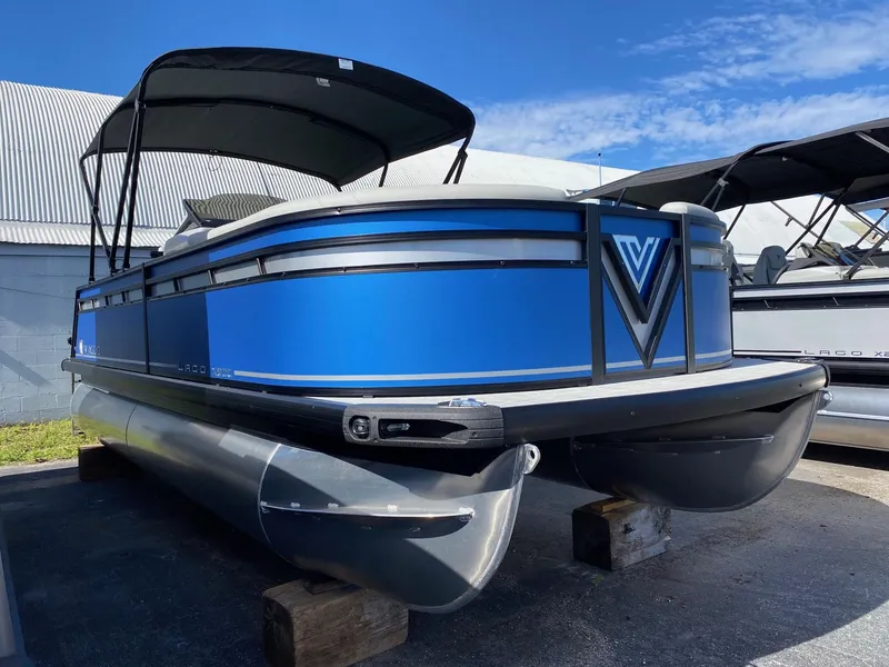 Slide: The Image of 2024 Viaggio Lago 20C pontoon boat with blue exterior, docked outdoors under a clear sky. - 2