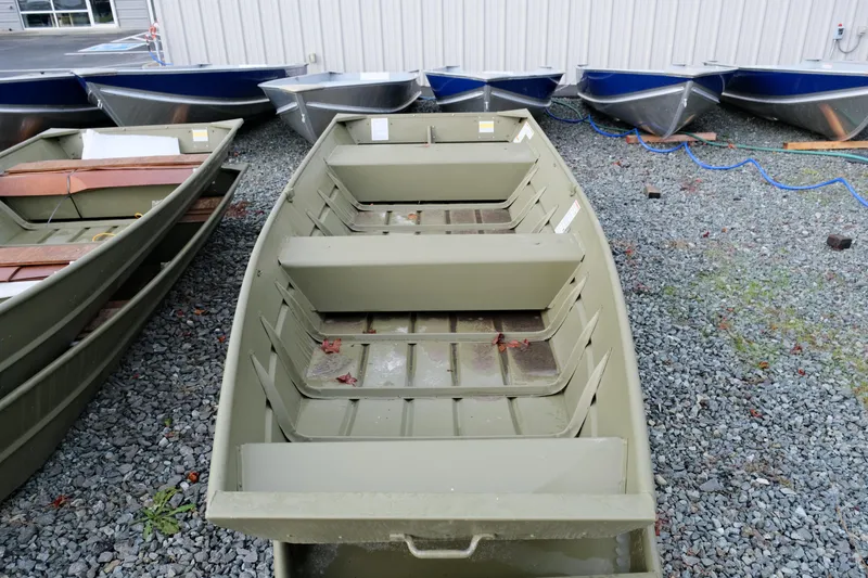 Slide: The Image of 2024 Crestliner 1436L CR Jon boat on gravel lot, surrounded by other boats. - 5