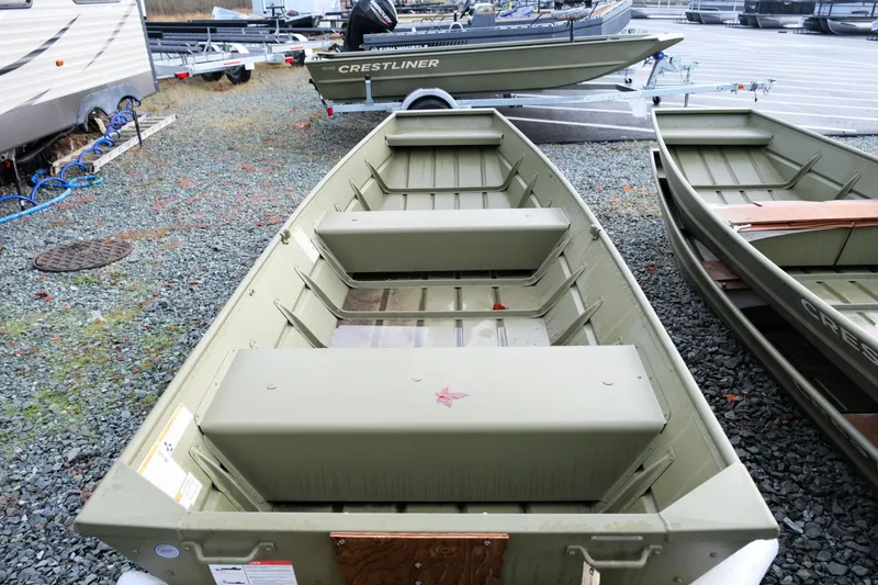 Slide: The Image of 2024 Crestliner 1436L CR Jon boat on gravel lot, showcasing interior seating and design. - 6