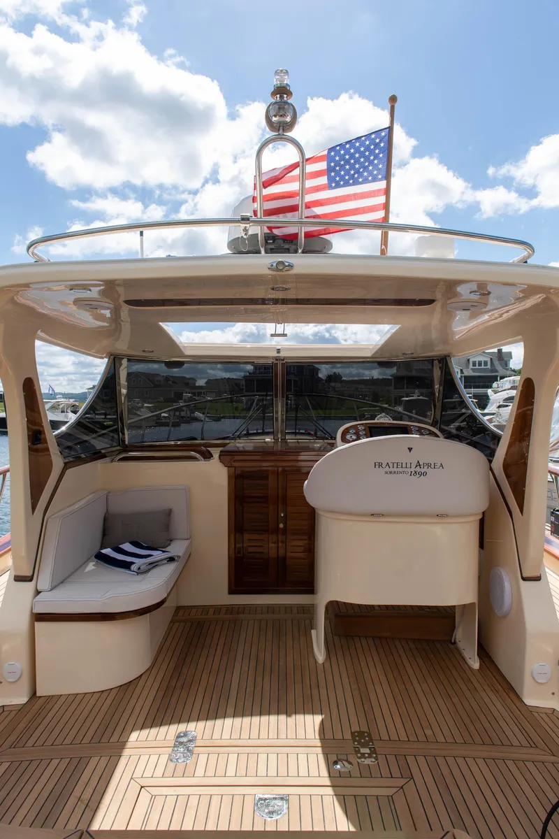 Slide: The Image of 2020 Fratelli Aprea Sorrento 32 yacht with American flag, wooden deck, and seating area. - 11
