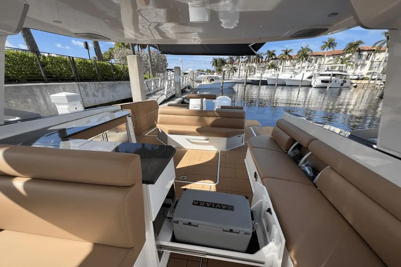 Slide: The Image of 2024 Aviara AV40 Outboard luxury boat interior with tan seating and marina view. - 15