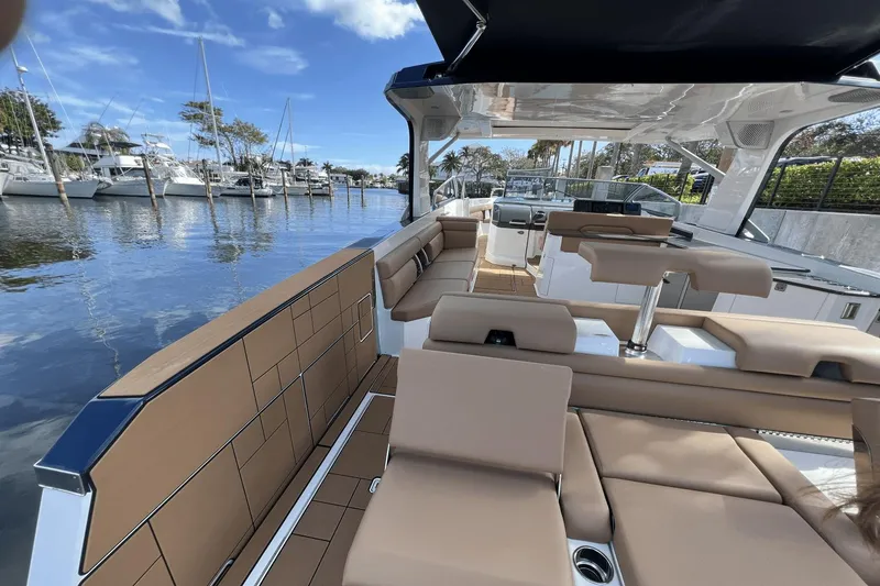 Slide: The Image of 2024 Aviara AV40 Outboard luxury boat interior with tan seating and marina view. - 7