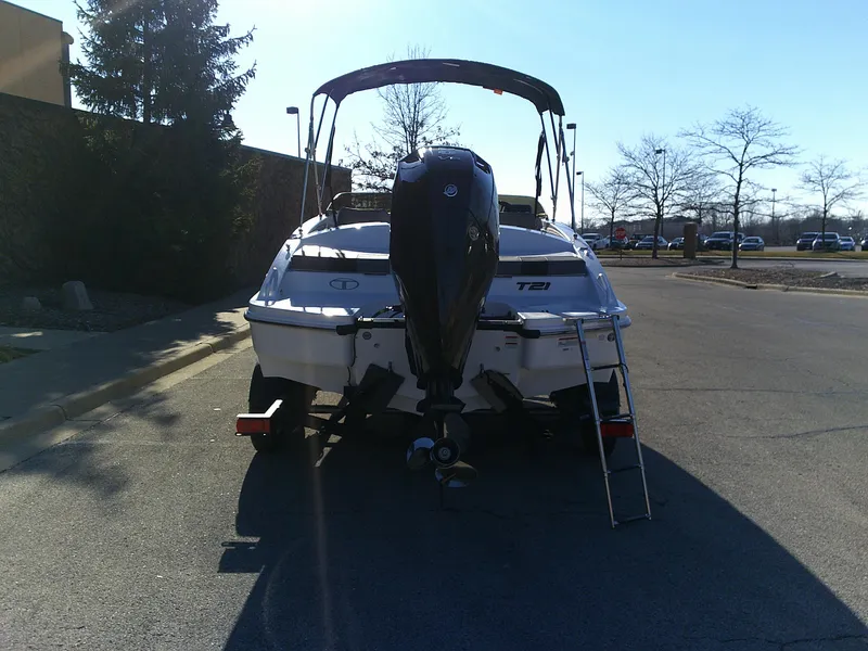 Slide: The Image of 2024 Tahoe T21 boat with outboard motor and ladder, parked on a sunny day. - 8