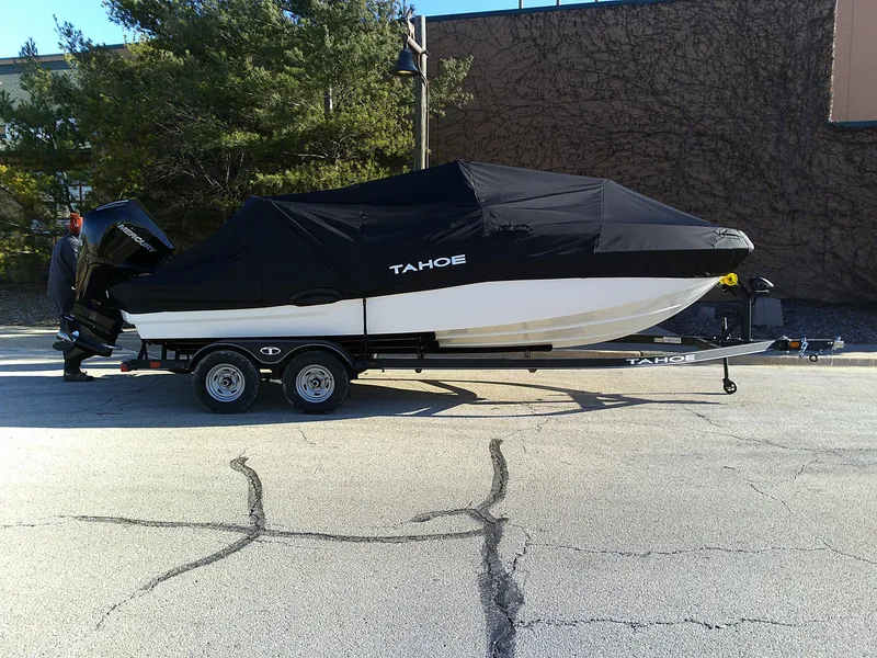 Slide: The Image of 2024 Tahoe T21 boat on trailer with black cover in parking lot. - 9