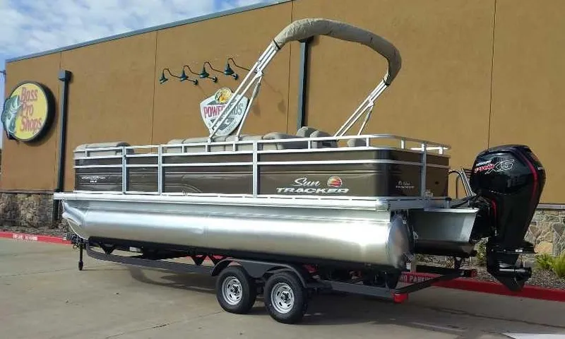 Slide: The Image of 2024 Sun Tracker SportFish 22 DLX pontoon boat on trailer outside Bass Pro Shops. - 2