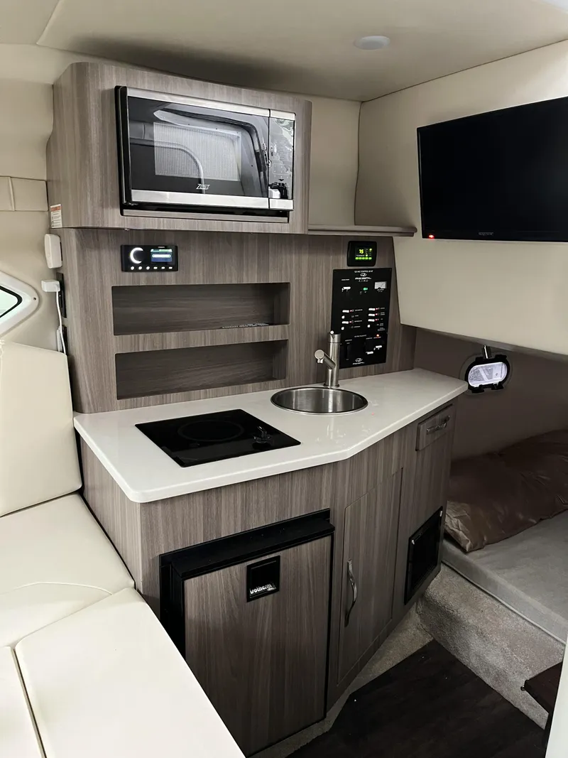 Slide: The Image of 2022 Regal 26XO boat interior with kitchenette, microwave, sink, and TV. - 17