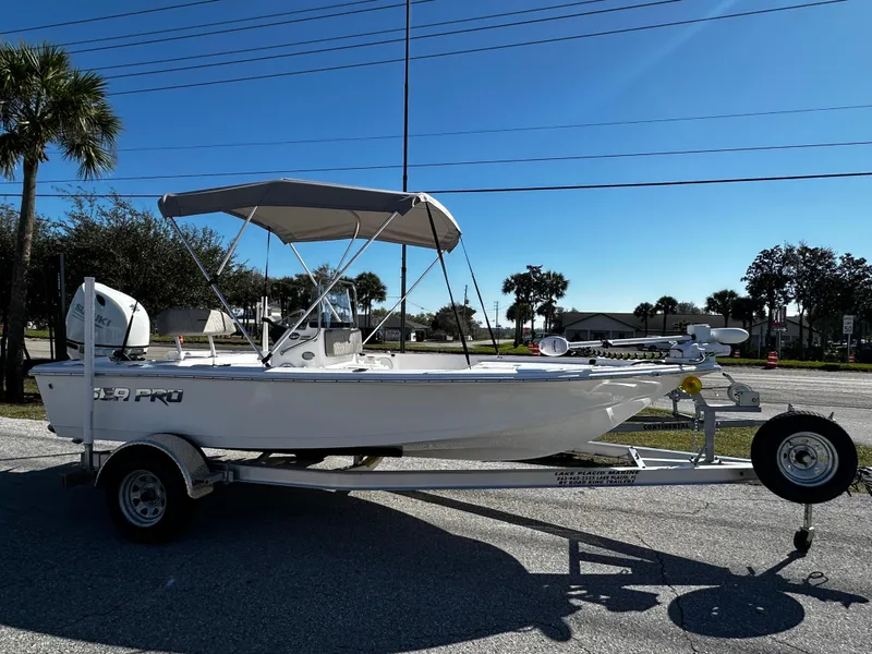 Slide: The Image of 2024 Sea Pro 172 Bay boat on trailer with canopy, parked outdoors. - 2