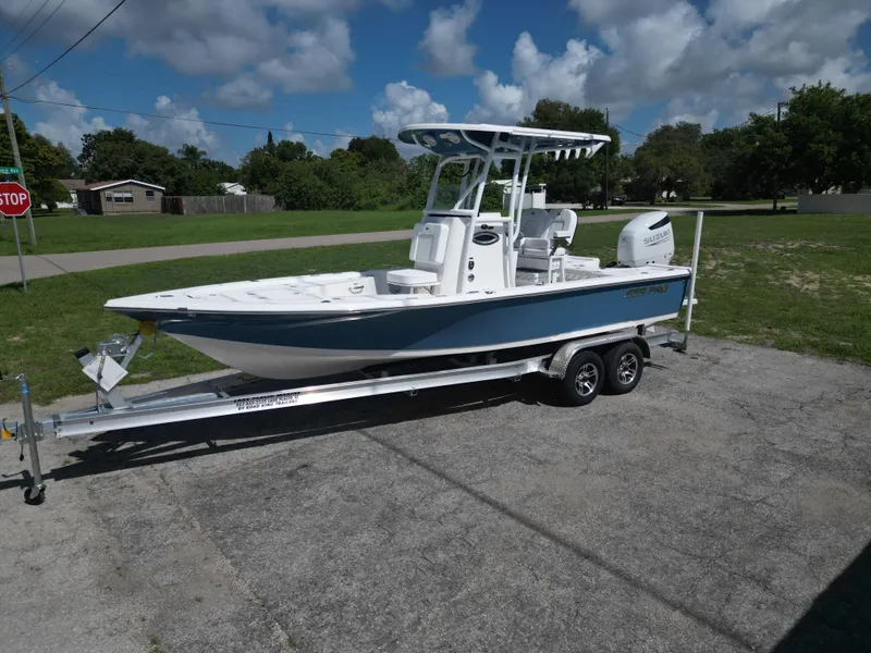 Slide: The Image of 2024 Sea Pro 230 Bay boat on a trailer under a partly cloudy sky. - 2