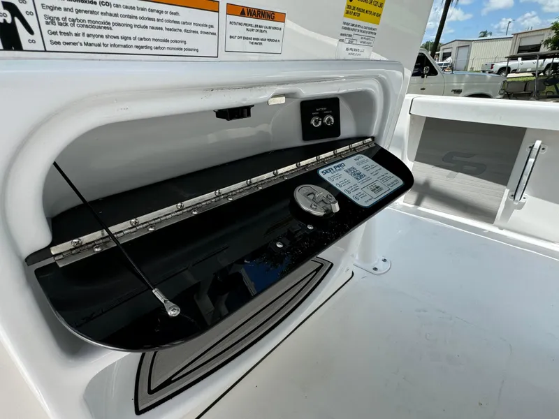 Slide: The Image of 2024 Sea Pro 230 Bay boat storage compartment with warning labels and control panel. - 26