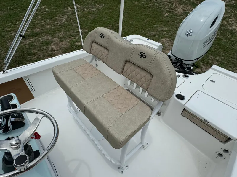 Slide: The Image of 2024 Sea Pro 210 Bay boat with beige cushioned seating and Suzuki outboard motor. - 23