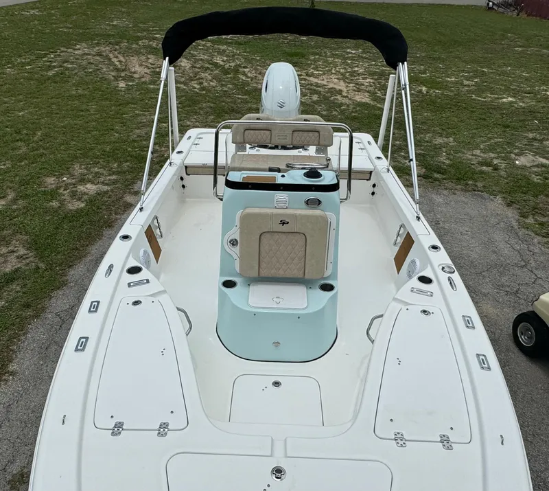 Slide: The Image of 2024 Sea Pro 210 Bay boat with center console and seating, docked on grass. - 9