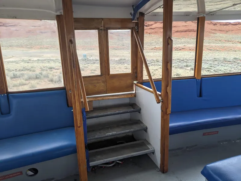 Slide: The Image of Interior of a 1987 custom tour boat with blue seating and wooden accents. - 16