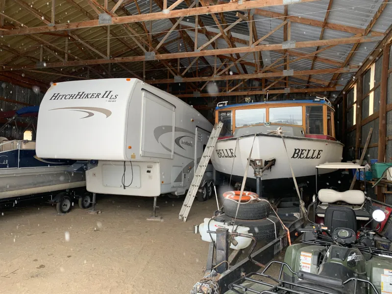 Slide: The Image of Tour boat and RV stored in a large wooden shed. - 22