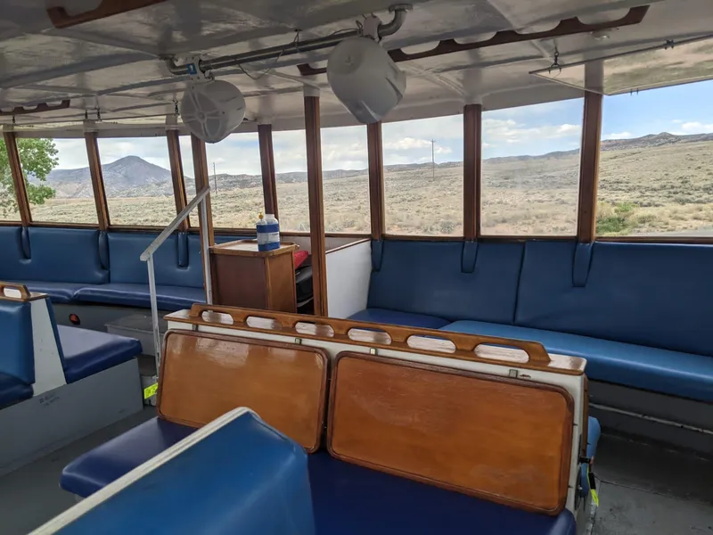 Slide: The Image of Interior of a 1987 custom tour boat with blue seating and panoramic windows. - 8