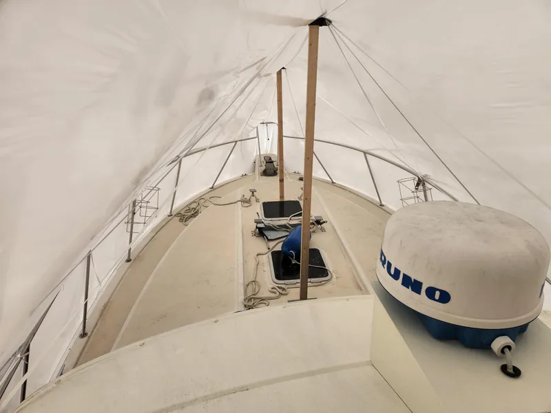 Slide: The Image of 1988 Silverton 40 Convertible yacht under protective cover, showcasing deck and equipment. - 15