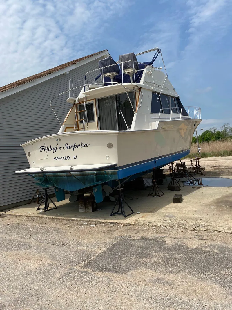 Slide: The Image of 1988 Silverton 40 Convertible boat on stands, named "Friday's Surprise," in a marina setting. - 2