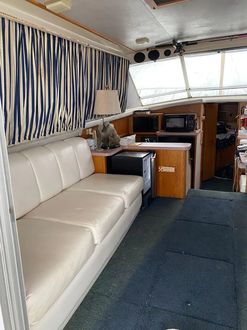 Slide: The Image of 1988 Silverton 40 Convertible interior with white sofa, striped curtains, and kitchenette. - 24