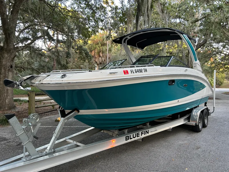 Slide: The Image of 2022 Sea Ray SDX 270 Outboard boat on a Blue Fin trailer in a wooded area. - 2