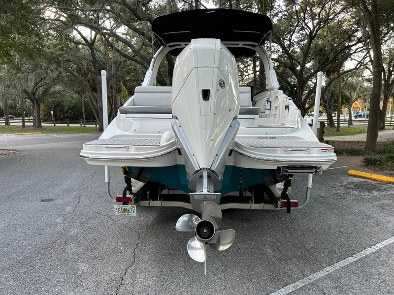 Slide: The Image of 2022 Sea Ray SDX 270 Outboard boat, rear view, parked in a wooded area. - 5