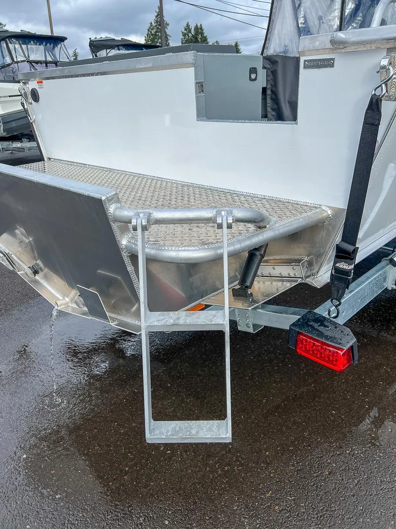 Slide: The Image of 2025 Hewescraft 210 Sea Runner ET boat stern with ladder and trailer. - 19