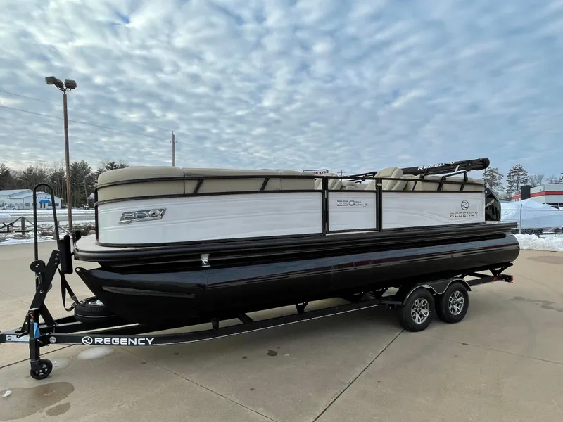 Slide: The Image of 2024 Regency 230 DL3 pontoon boat on a trailer under a cloudy sky. - 2